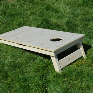 cornhole bois naturel avec veinage et nœuds apparents, sur le gazon, vue de derrière