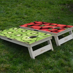 cornhole 2 planches fraises et kiwis, et encore des fraises et encore des kiwis, sur le gazon, vue de derrière