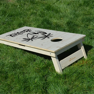 cornhole surfeur avec sa planche sous les palmiers, sur le gazon, vue de derrière