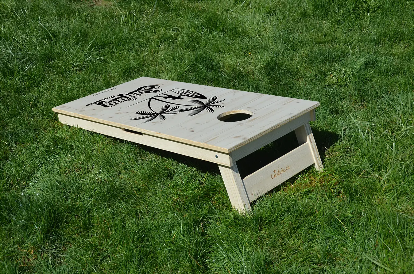 cornhole surfeur avec sa planche sous les palmiers, sur le gazon, vue de derrière