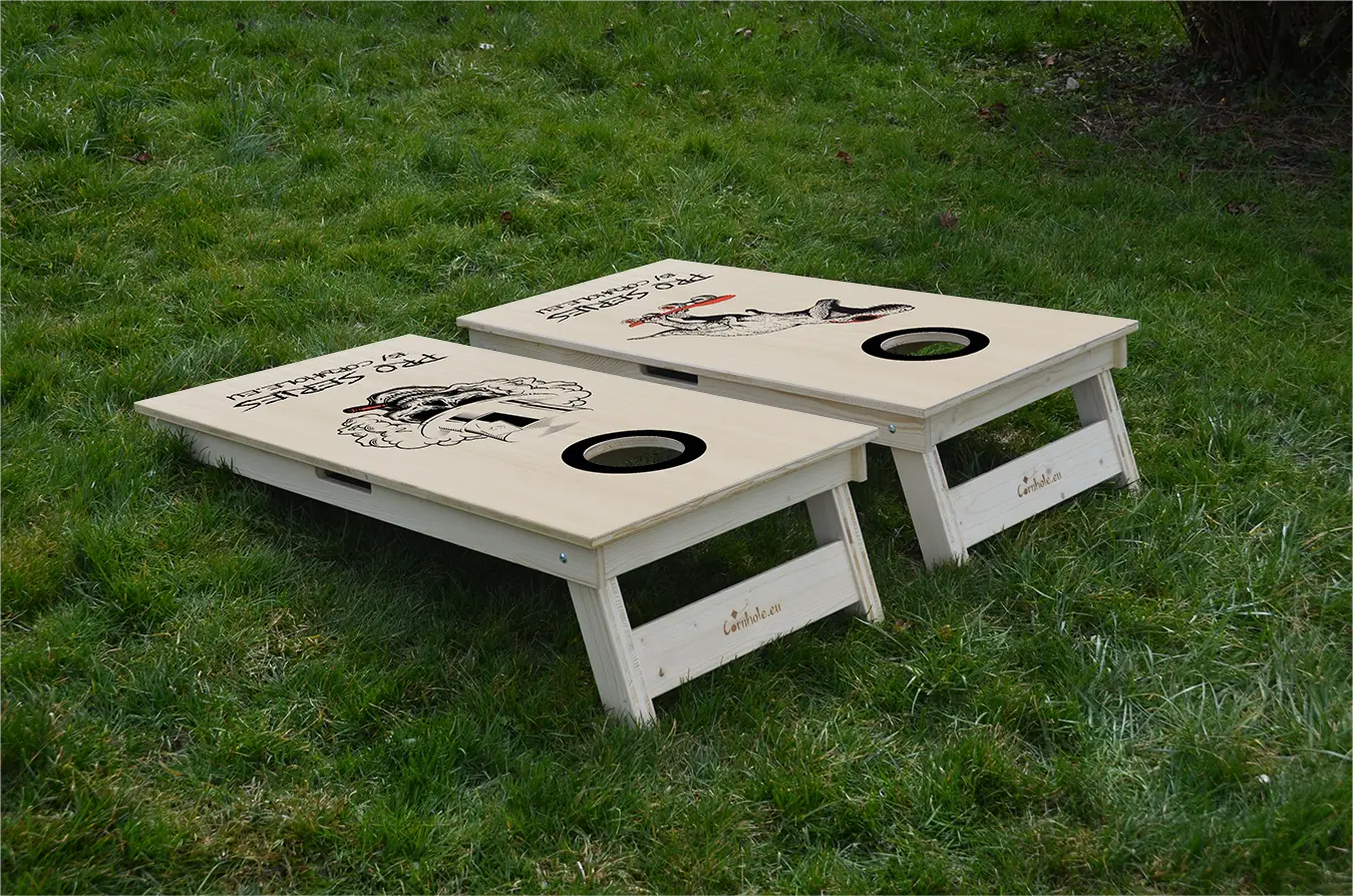 cornhole Pro de compétition deux planches t-rex sur son skate et tête de mort, sur le gazon, vue de derrière